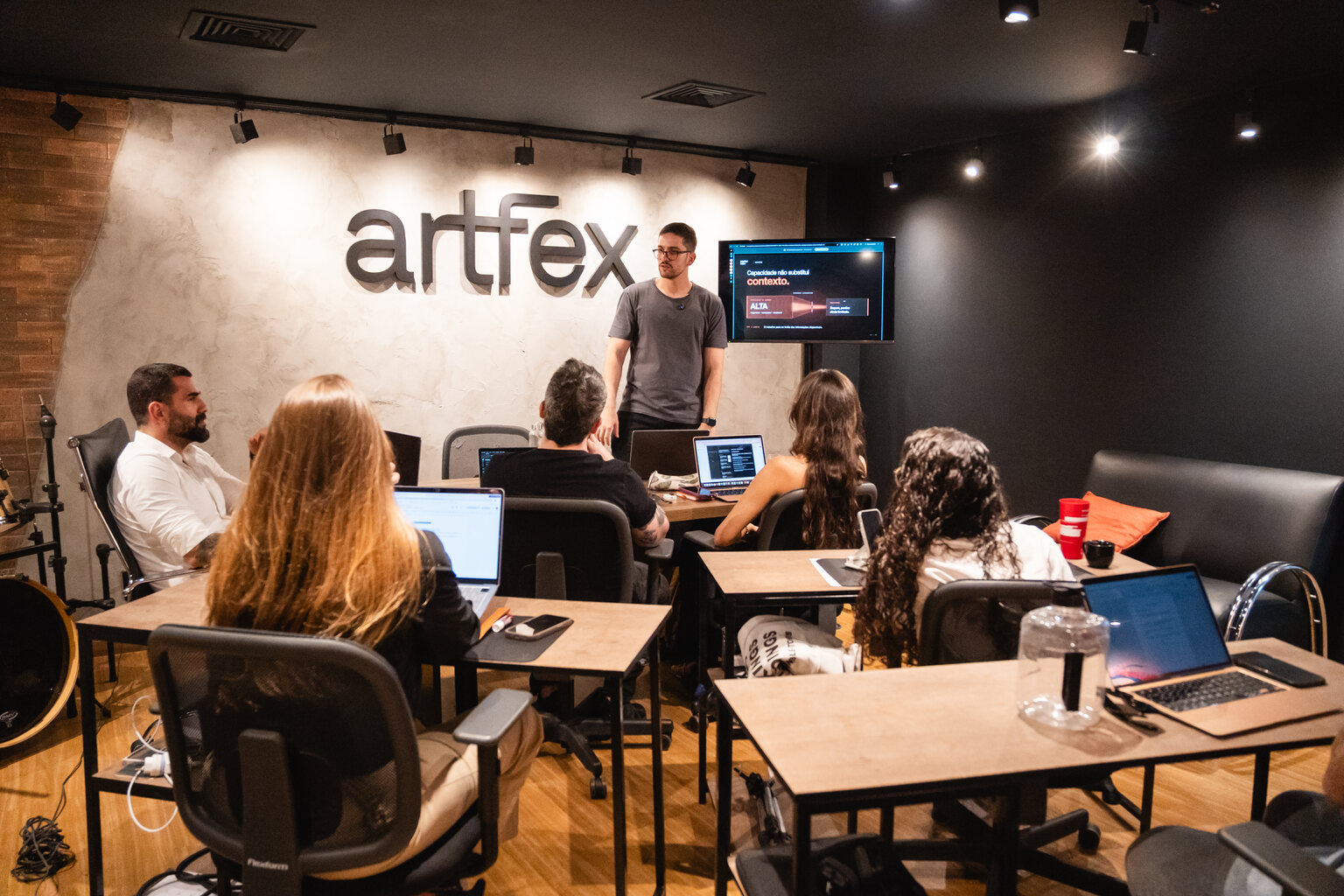 Pedro Lobo conduz um treinamento de IA com a equipe da Artfex reunida diante de seus computadores.